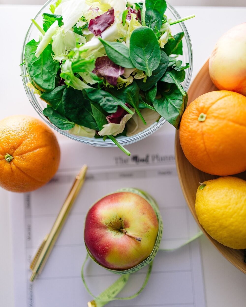 Persiapan makan sehat dengan salad, buah, dan alat perencanaan menu